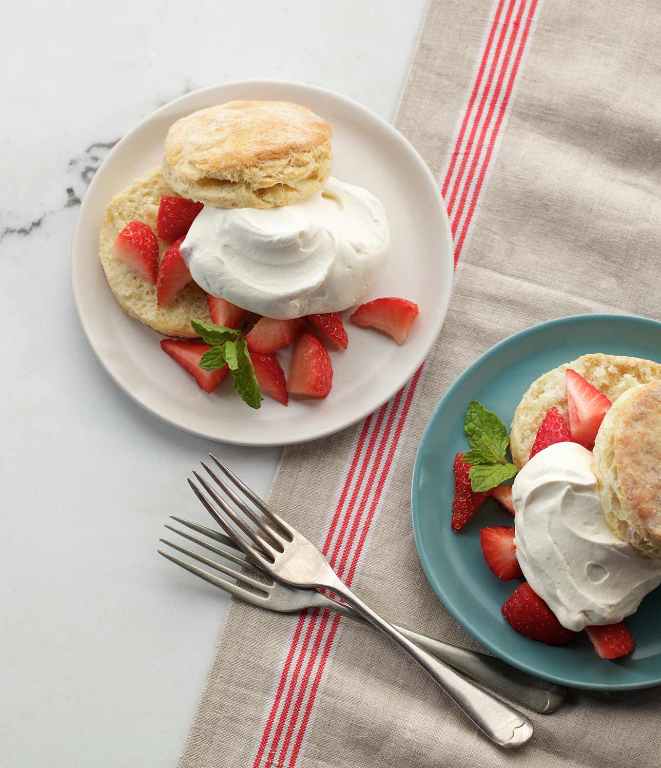 Fresh cut strawberries layered between a cut biscuit with whipping cream.