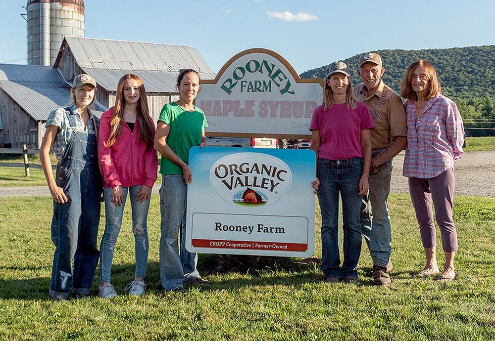 The Rooney family standing in front of their Organic Valley farm sign